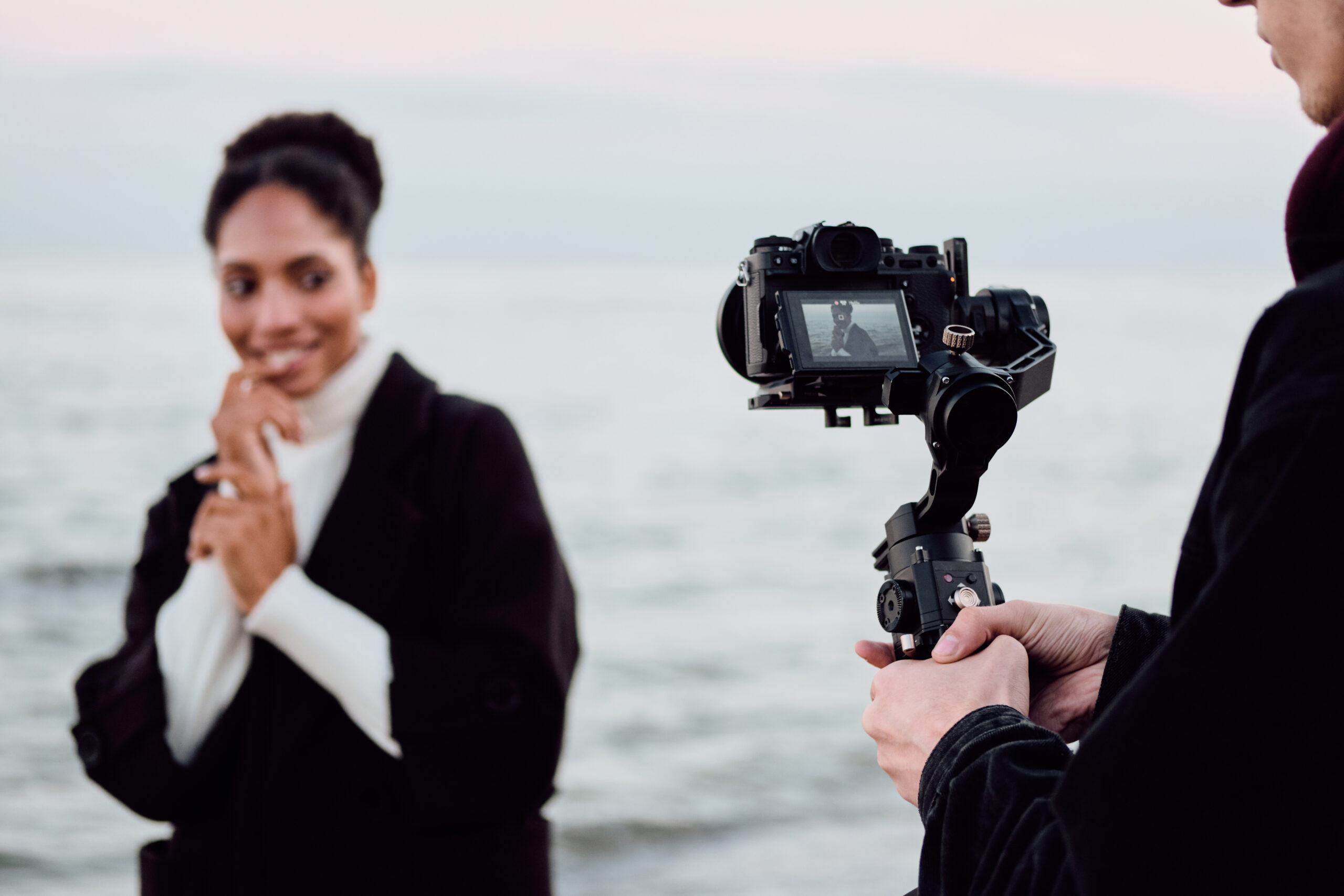 Pretty cute African American girl happily posing on camera during photo session by the sea